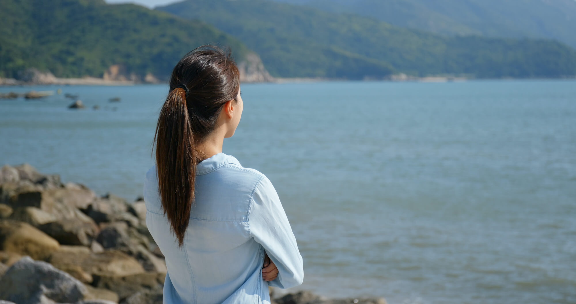 Woman with dark hair looking out to sea, contemplating victims of crime compensation